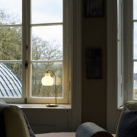 Living room with a lamp on a windowsill and a view of trees outside.