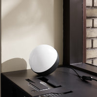 Modern spherical lamp in black and white, featuring a sleek, minimalist design against a textured background.