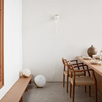 White walls and furniture, with natural wood tones and soft round shapes in white and beige, create a minimalist aesthetic.