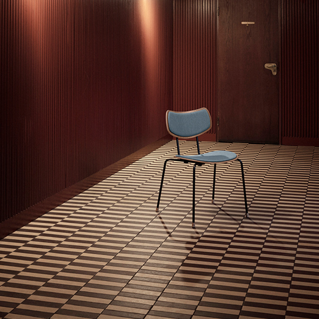 Blue chair on a patterned brown and cream tiled floor with a rich wooden backdrop. Stylish modern interior design.