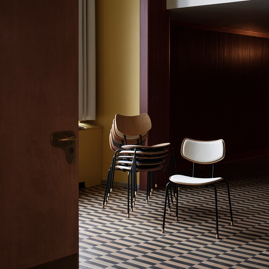 Stack of chairs in warm brown and white tones on a geometric black and cream patterned floor.