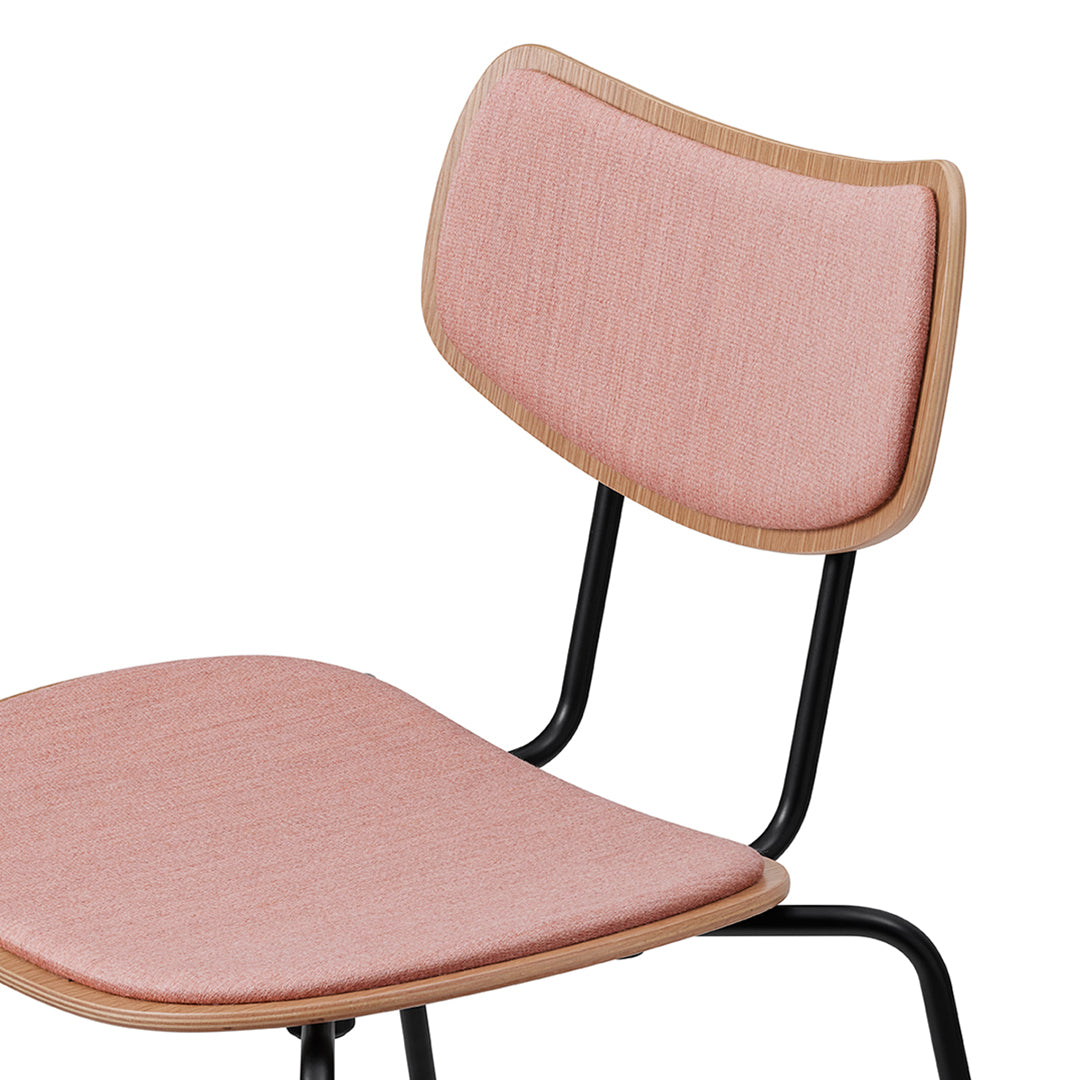 Pink upholstered chair with textured fabric and natural wood accents, set on a sleek black metal frame.