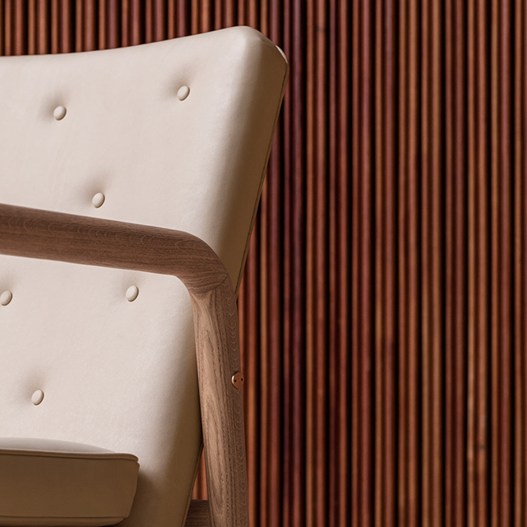 Stylish beige chair with tufted detailing, set against a rich wood-paneled background. Modern and elegant design.