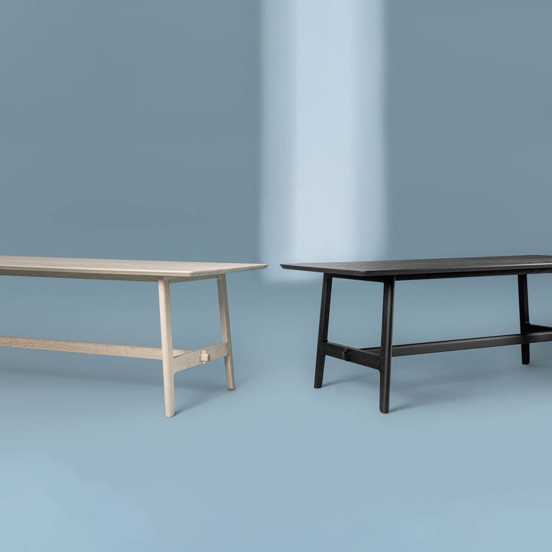 "Neutral beige and sleek black wooden tables on a soft blue background, showcasing minimalist design."