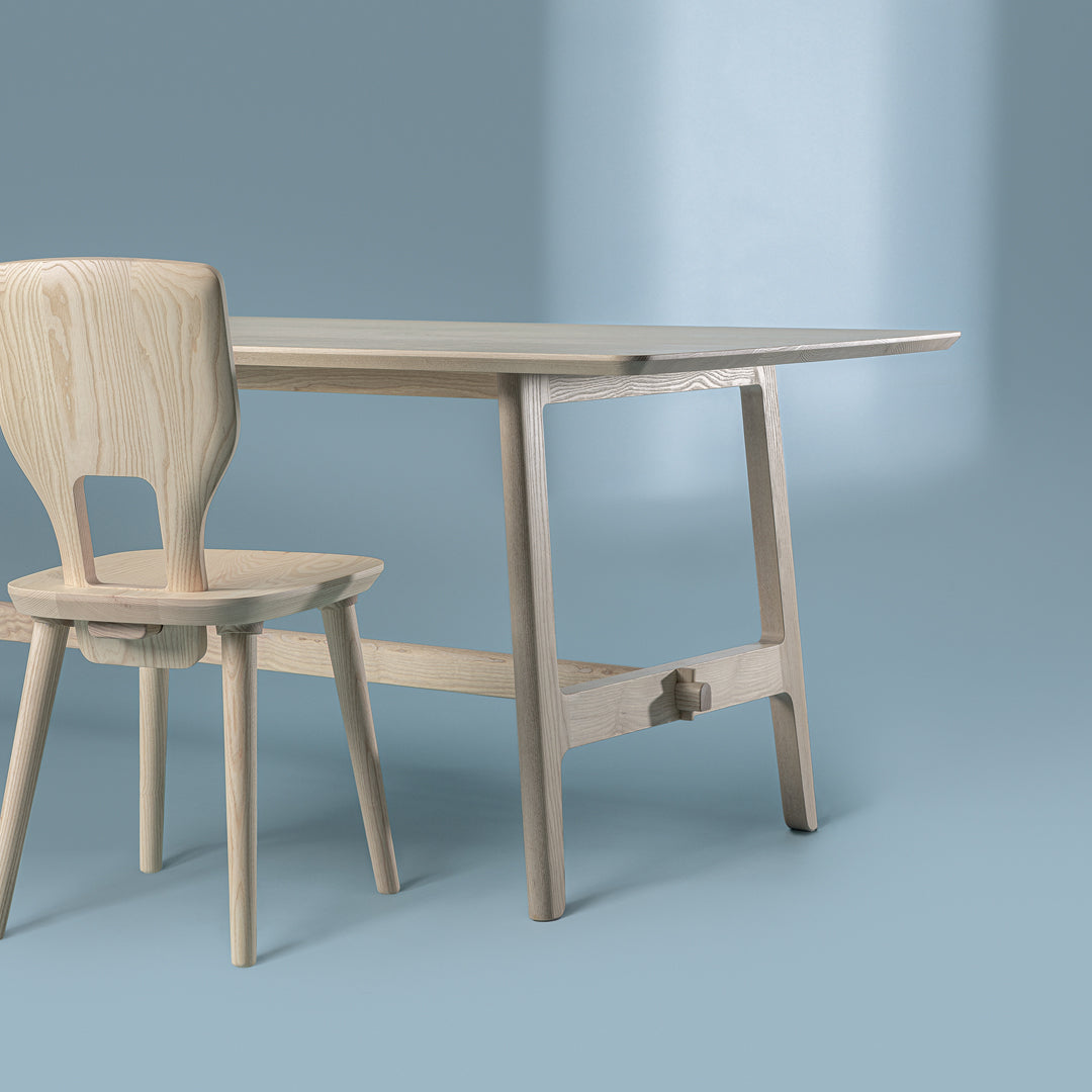 Light wood dining table and chair set against a soft blue background, featuring clean lines and minimalistic design.
