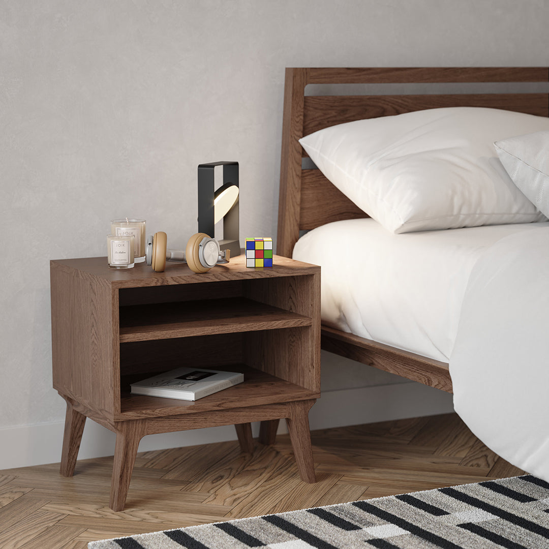 Wooden nightstand with a natural finish, paired with a black and white striped rug. Soft neutral bedroom colors.