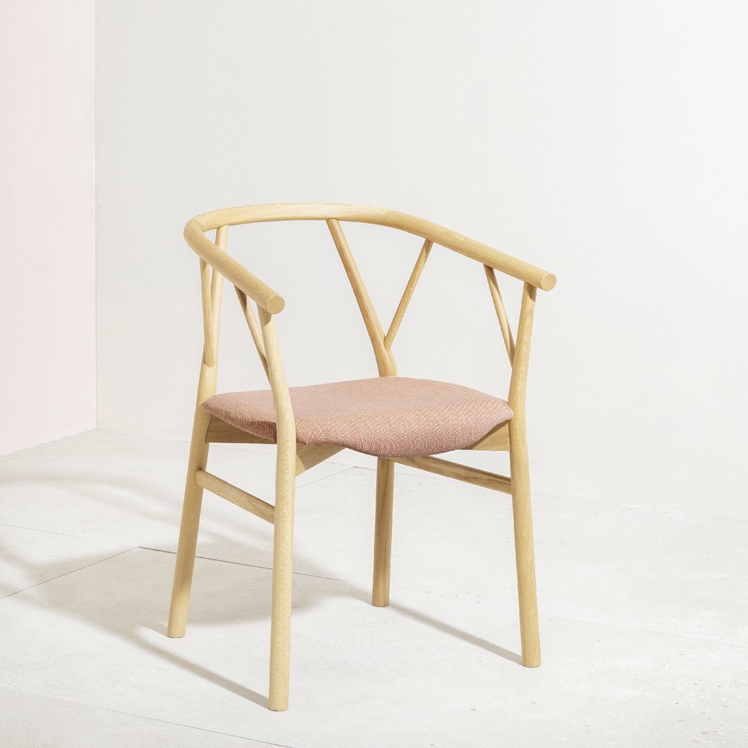 Light wood chair with a minimalist design and soft pink fabric cushion, featuring clean lines and a natural finish.