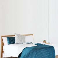 Teal and white bedding set featuring geometric patterns on a stylish wooden bed frame.