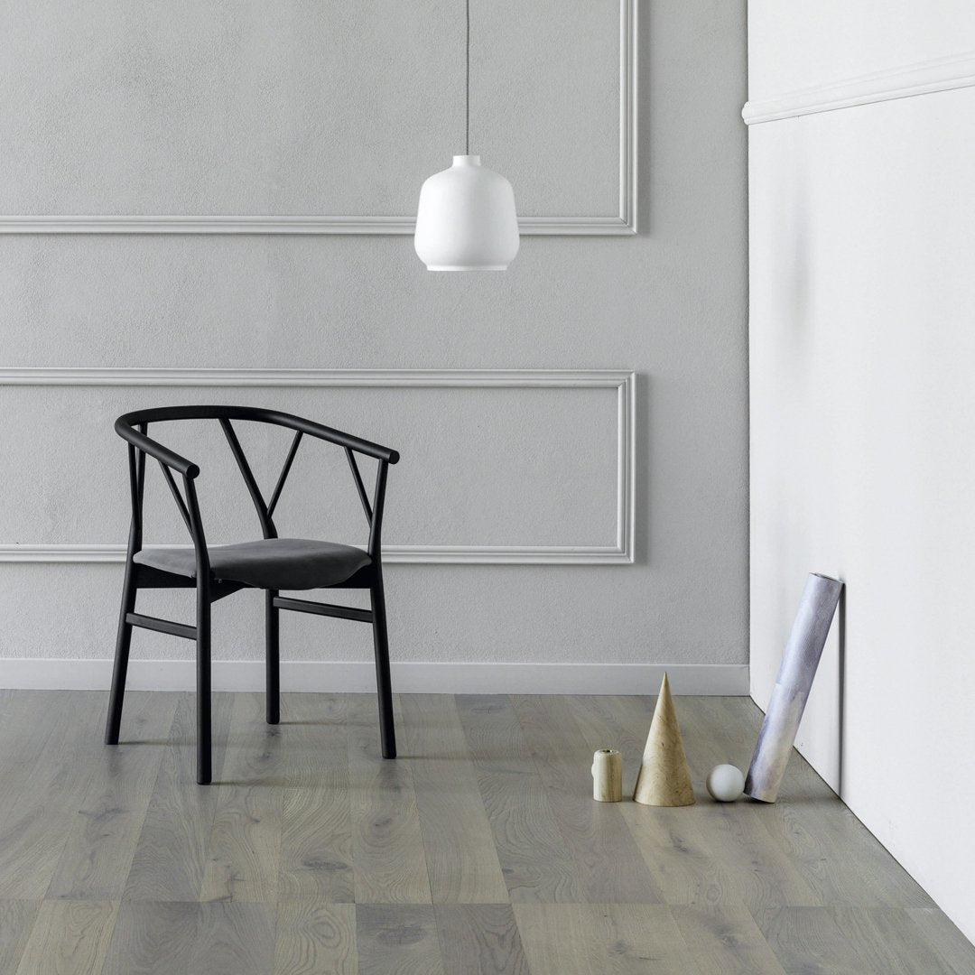 Black chair with a minimalist design against a soft gray wall and light wood floor, featuring geometric decor accents.