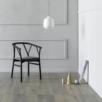 Black chair with a minimalist design against a soft gray wall and light wood floor, featuring geometric decor accents.