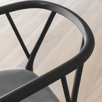 Black metal chair frame with sleek, minimalist lines and a smooth gray seat, set against light wooden flooring.