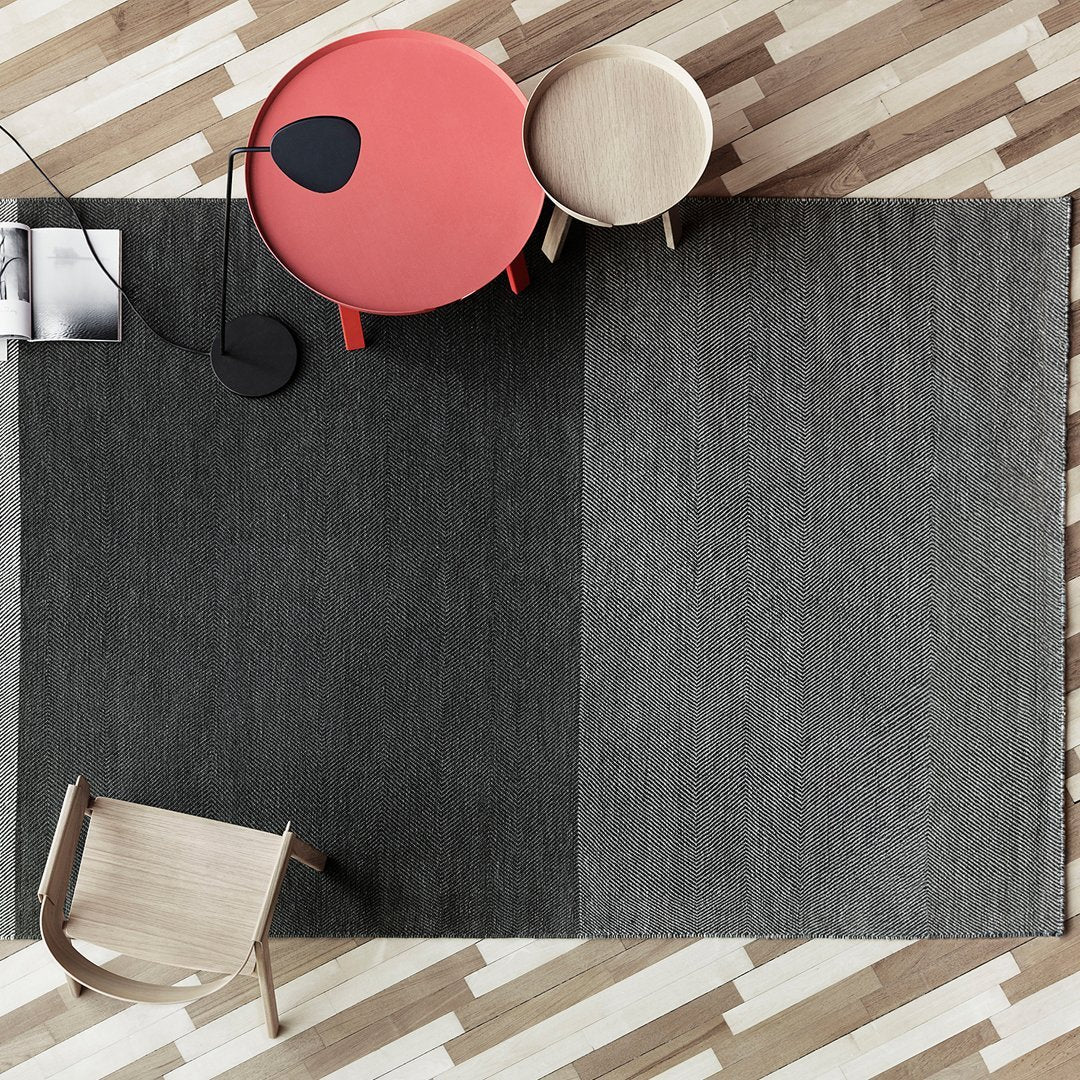 "Gray patterned area rug with a modern design, complementing a minimalist room with light wood flooring."