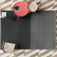"Gray patterned area rug with a modern design, complementing a minimalist room with light wood flooring."