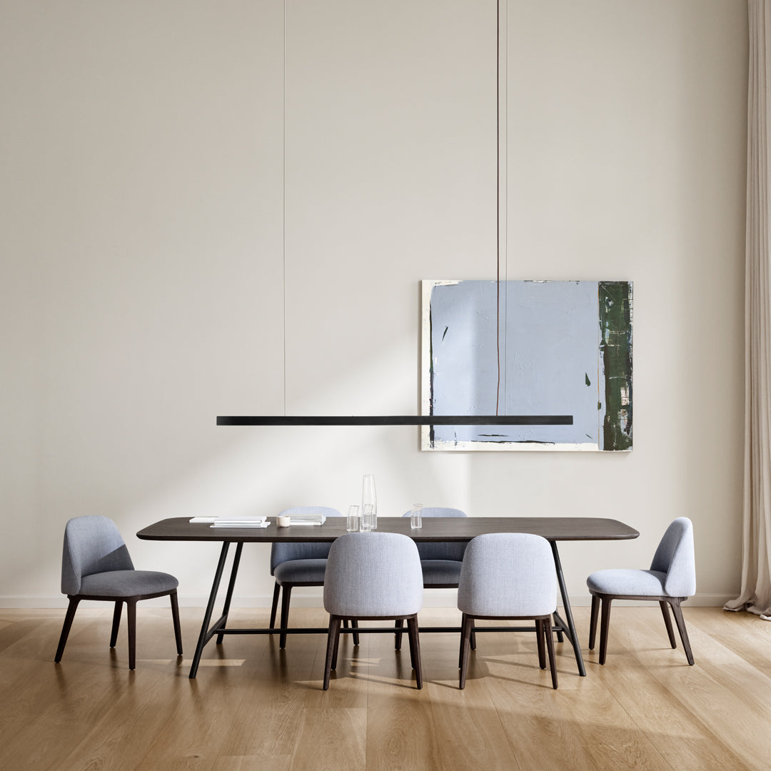 Modern dining table with a sleek dark wood finish, complemented by soft light blue upholstered chairs.