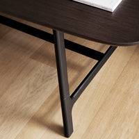 Dark wood tabletop with sleek black legs, showcasing a minimalist design against light wooden flooring.