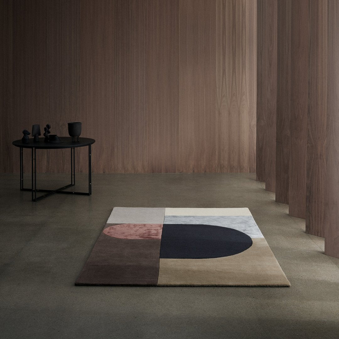 Geometric patterned rug with soft neutral tones, including beige, grey, brown, and navy blue accents.