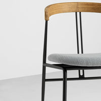 Modern chair featuring a sleek gray seat, wooden armrest, and minimalist black metal frame. Elegant, contemporary design.