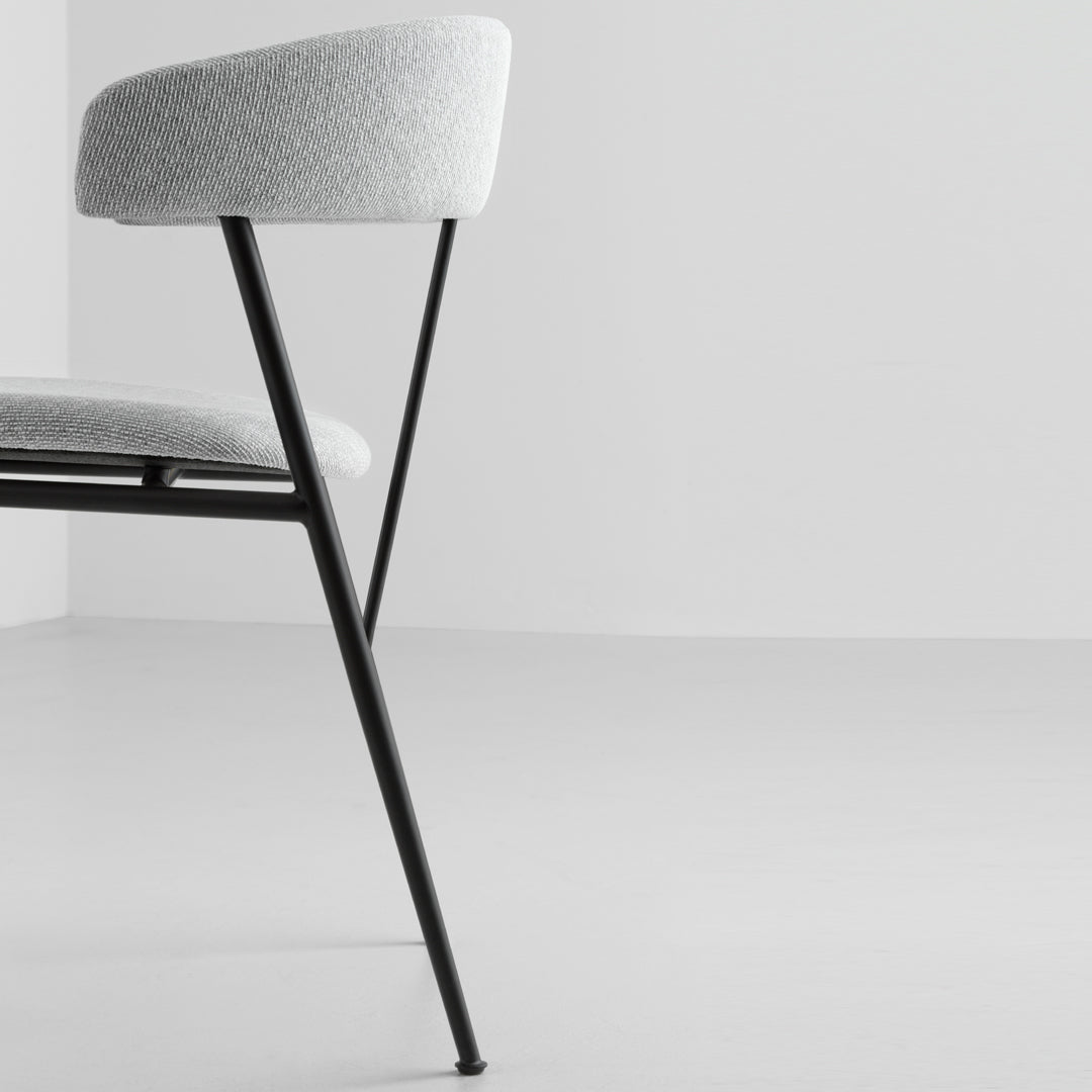 Gray upholstered chair with a minimalist design and sleek black legs, set against a light gray background.