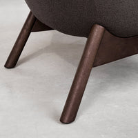 Dark brown wooden legs support a sleek, rounded charcoal fabric seat, showcasing a minimalistic and modern design.