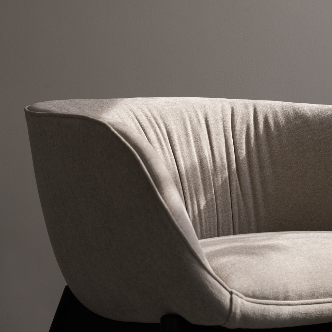 Light gray upholstered chair with subtle vertical pleats, featuring a modern, minimalist design.