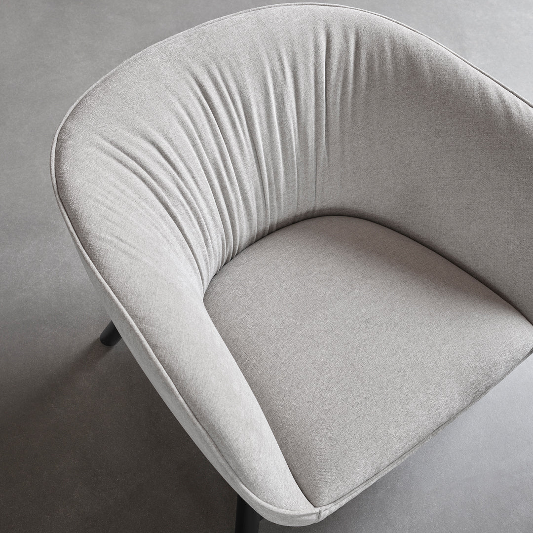 Soft grey upholstered chair with pleated detailing and sleek black legs, ideal for modern decor.