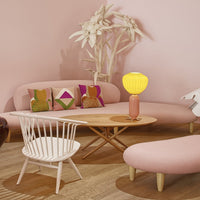 "Cozy living room featuring pink and beige tones, vibrant patterned cushions, and a soft yellow lamp."