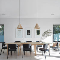 Modern dining room featuring black chairs and natural wood table, complemented by neutral walls and minimalist decor.