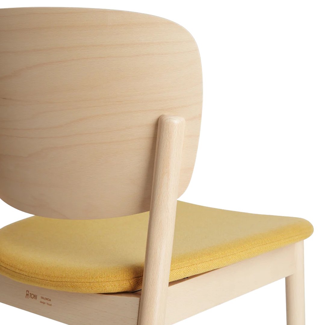 Light wood chair with a smooth, rounded back and a bright yellow, cushioned seat. Simple, modern design.