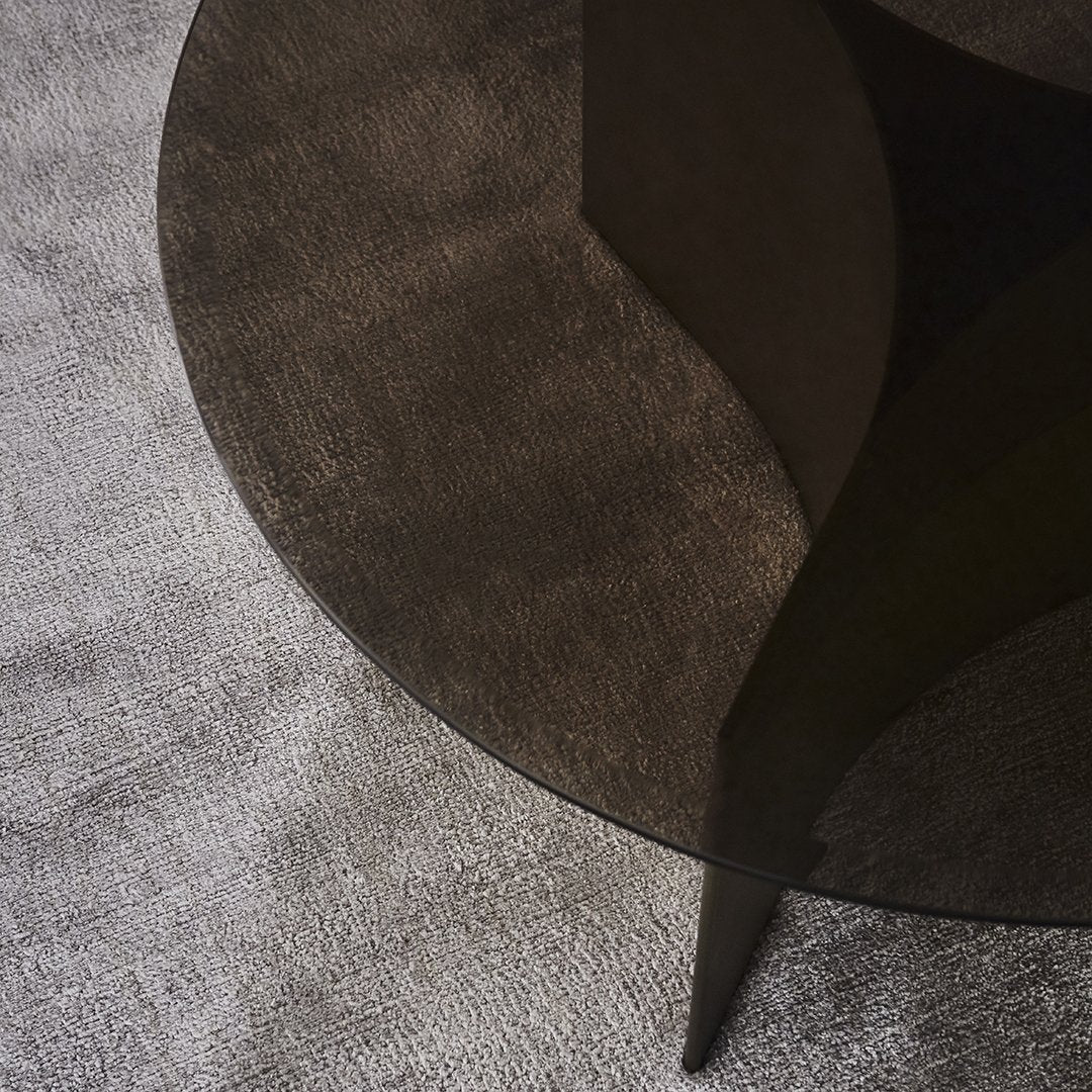 Black circular table on a textured gray surface, featuring a sleek, modern design and smooth lines.
