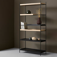 Modern black metal bookshelf with natural wood shelves, featuring a minimalist design against a warm brown background.