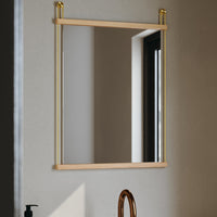 "Rectangular mirror with natural wood frame and gold accents, reflecting light in a modern bathroom setting."