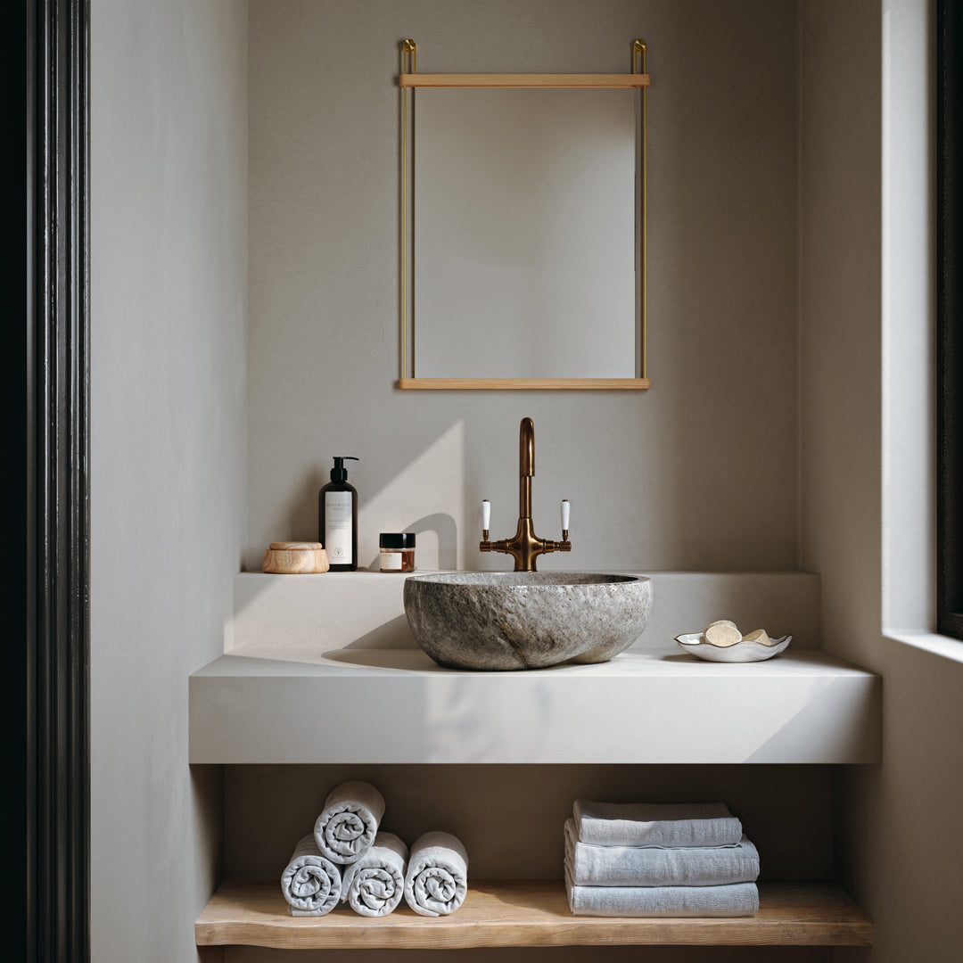 Elegant gray stone basin on a neutral wall, with warm wood tones and rolled white towels, creating a serene bathroom ambiance.
