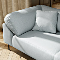 Light grey sofa with a smooth fabric finish and matching square cushion on a wooden floor backdrop.