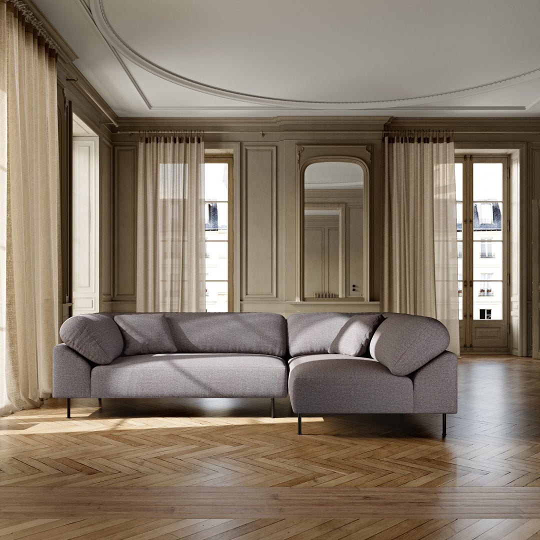 Light gray curved sofa with soft fabric and seamless design, set against elegant neutral-toned interior decor.