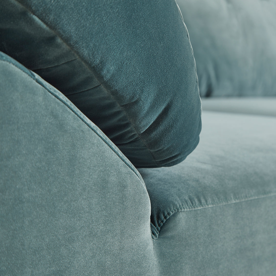 Teal velvet couch with textured fabric and a plush cushion, creating a modern, cozy look. Ideal for stylish interiors.