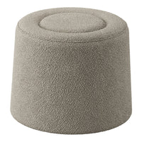 Soft beige upholstered pouf with textured surface and rounded top, perfect for modern decor.