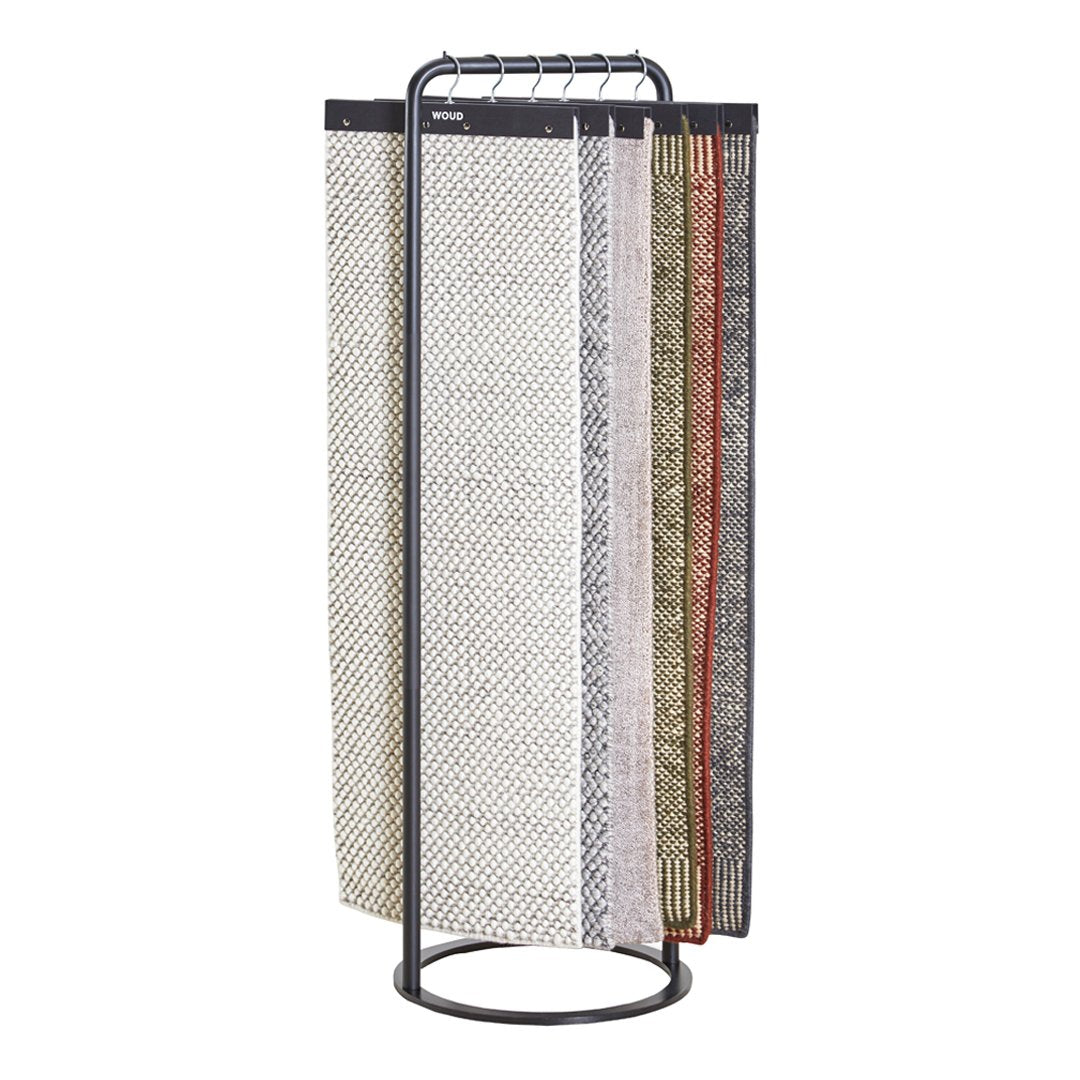 "Display of patterned fabrics featuring neutral tones with hints of red and green, arranged on a modern stand."