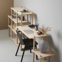 Light wood desk and shelves with black chair and gray vase, featuring minimalist design and neutral color scheme.