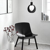 Black modern chair, white pendant light, and minimalist decor in a gray carpeted room with natural light.