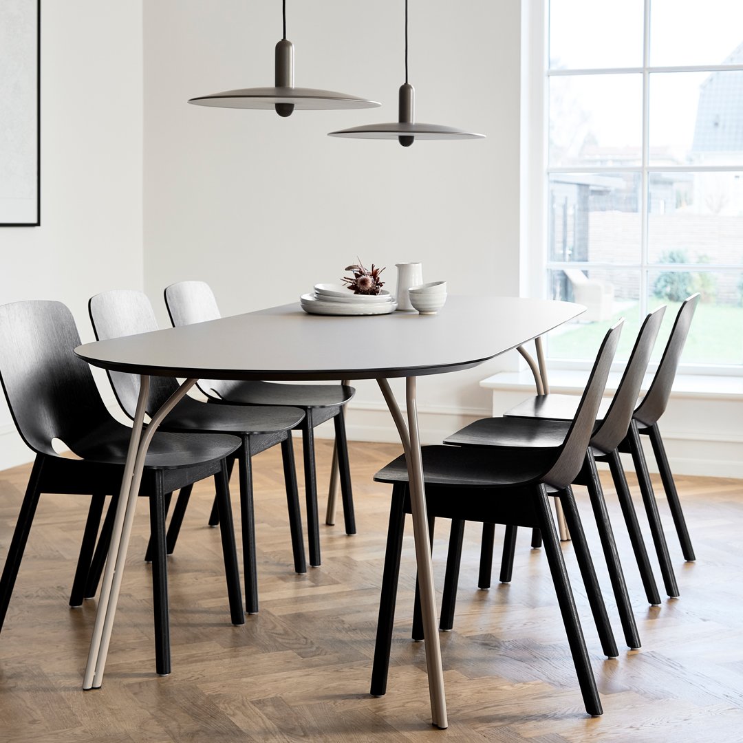 Modern dining table in gray with sleek black chairs, featuring minimalist design on light wood flooring.