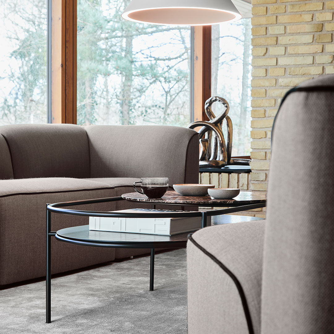 Modern living room with soft beige and brown tones, featuring a sleek black coffee table and textured upholstery.