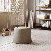 Neutral beige stool with a textured, rounded design, complementing a warm, minimalist interior setting.