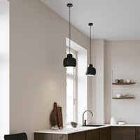 Black pendant lights against a soft beige wall, featuring clean lines and modern design. Perfect for contemporary interiors.
