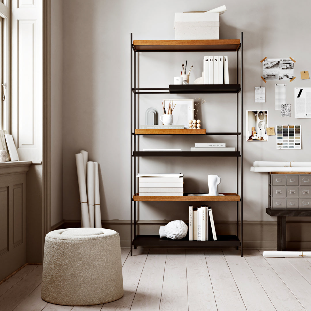 Black metal shelving unit with wooden shelves in a light, minimalist room featuring neutral tones and clean lines.