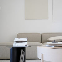 Minimalist living room in soft beige and white tones, featuring a black coffee table and light wooden accents.