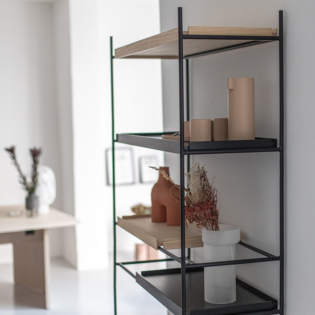 "Black metal shelving with wood accents, featuring terracotta and white vases, and dried flowers for a modern decor."