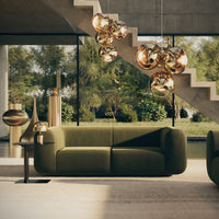 "Modern green sofa with metallic accents and warm lighting against a backdrop of nature and concrete."
