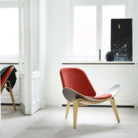 Mid-century modern chair with a red upholstered seat and smooth wooden frame; minimalist design, soft curves.