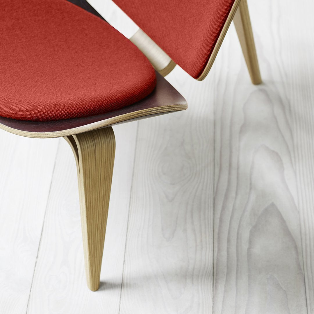Red upholstered chair with wooden legs and smooth, light-colored floor backdrop.