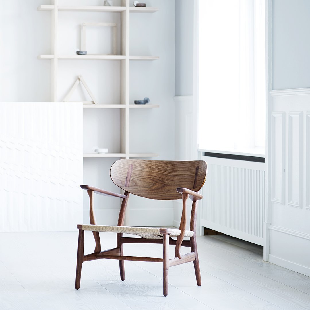 Mid-century modern chair in rich walnut, featuring a smooth wood grain and minimalistic design against a light backdrop.